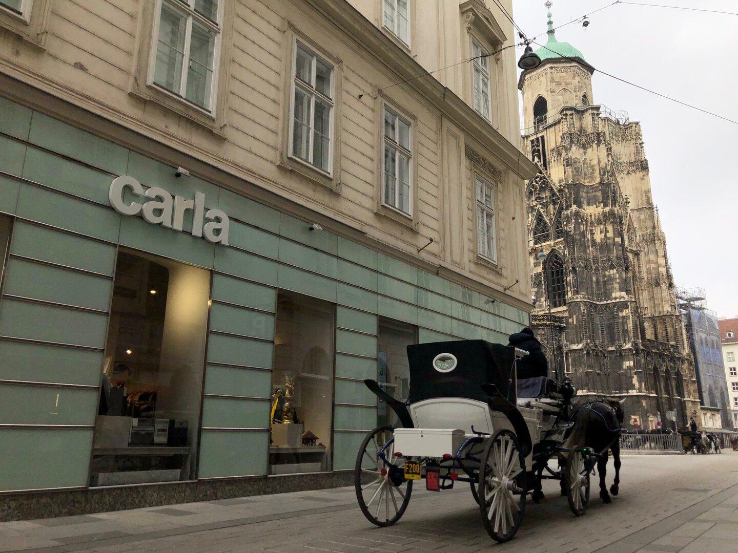 Eine Pferdekutsche vor dem Stephansdom in Wien, neben einem Geschäft namens „Carla“.