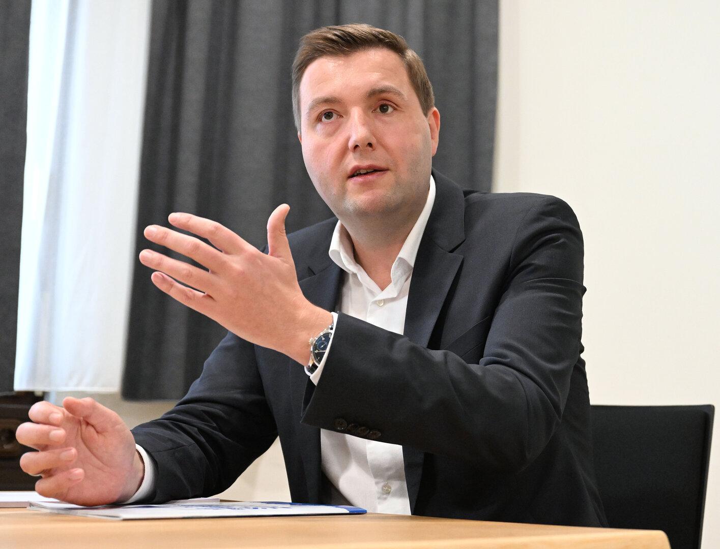 Ein Mann im Anzug gestikuliert an einem Tisch.