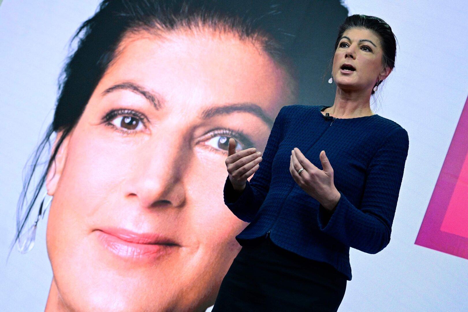Sahra Wagenknecht hält eine Rede vor einem großen Porträt von sich selbst.