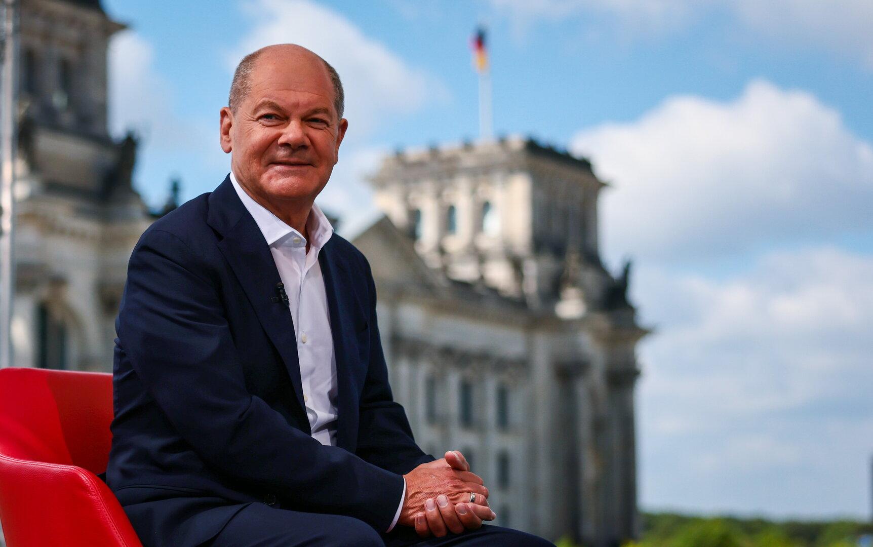 Olaf Scholz sitzt vor dem Reichstagsgebäude in einem roten Sessel.