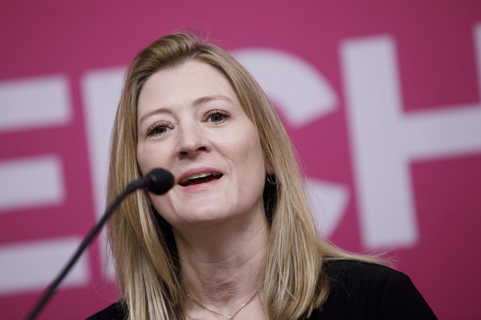 Eine Frau spricht bei einer Konferenz in ein Mikrofon.