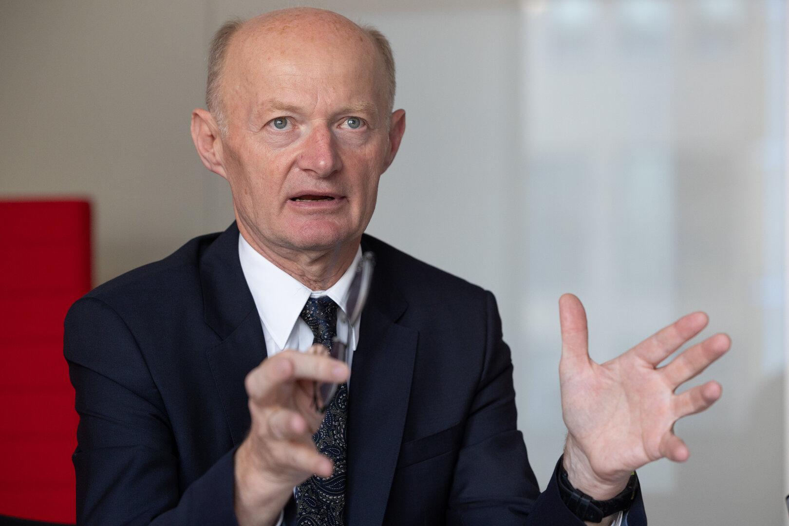 Ein Mann im Anzug gestikuliert während eines Gesprächs.