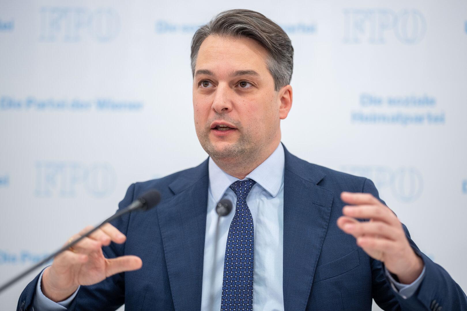 Ein Mann im Anzug spricht vor einem Mikrofon vor einem FPÖ-Hintergrund.