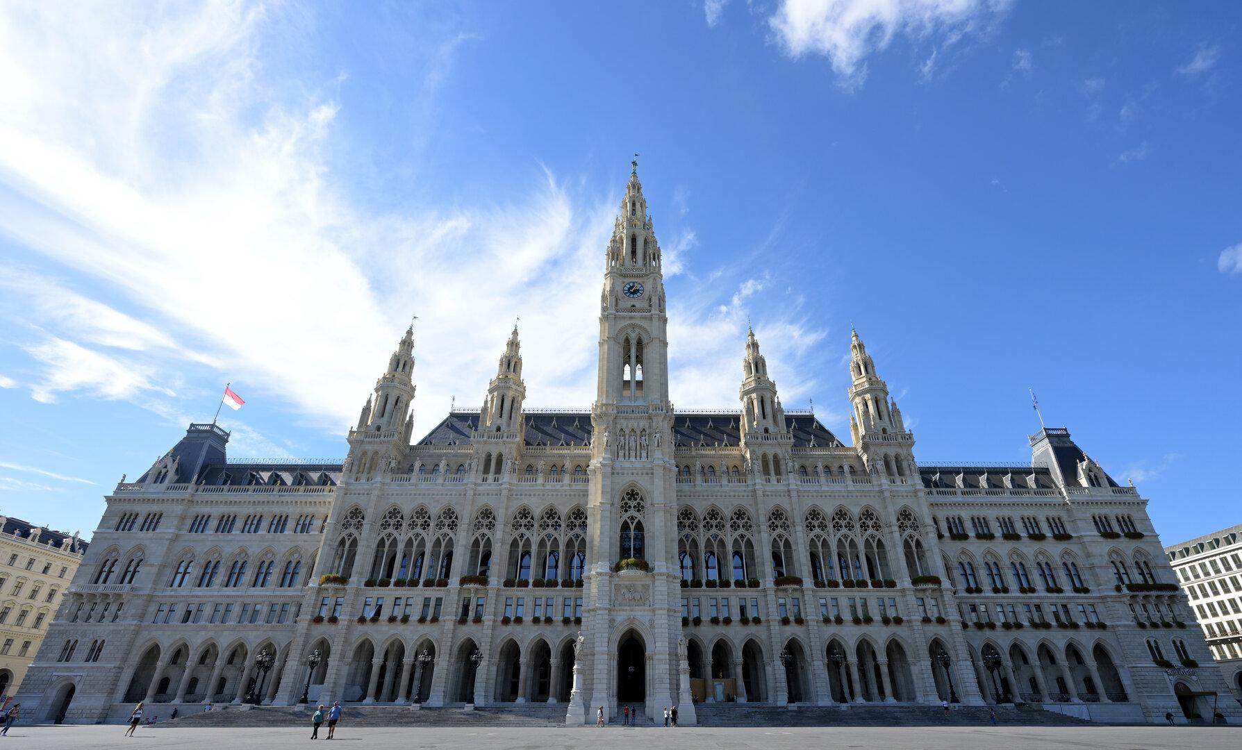 Das Wiener Rathaus mit seiner markanten Turmspitze unter blauem Himmel.