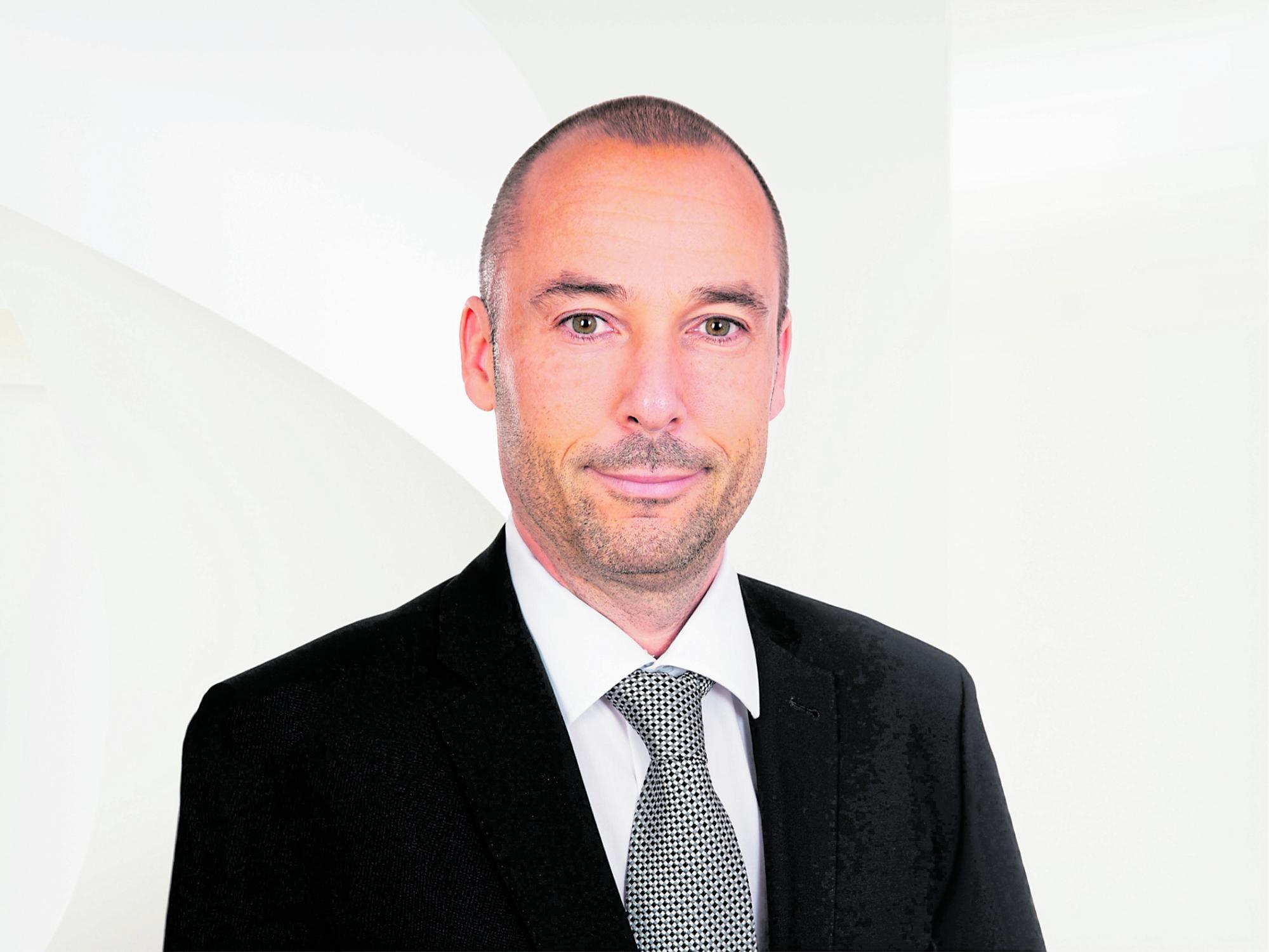 Roland Schatz in einem schwarzen Anzug mit Krawatte.