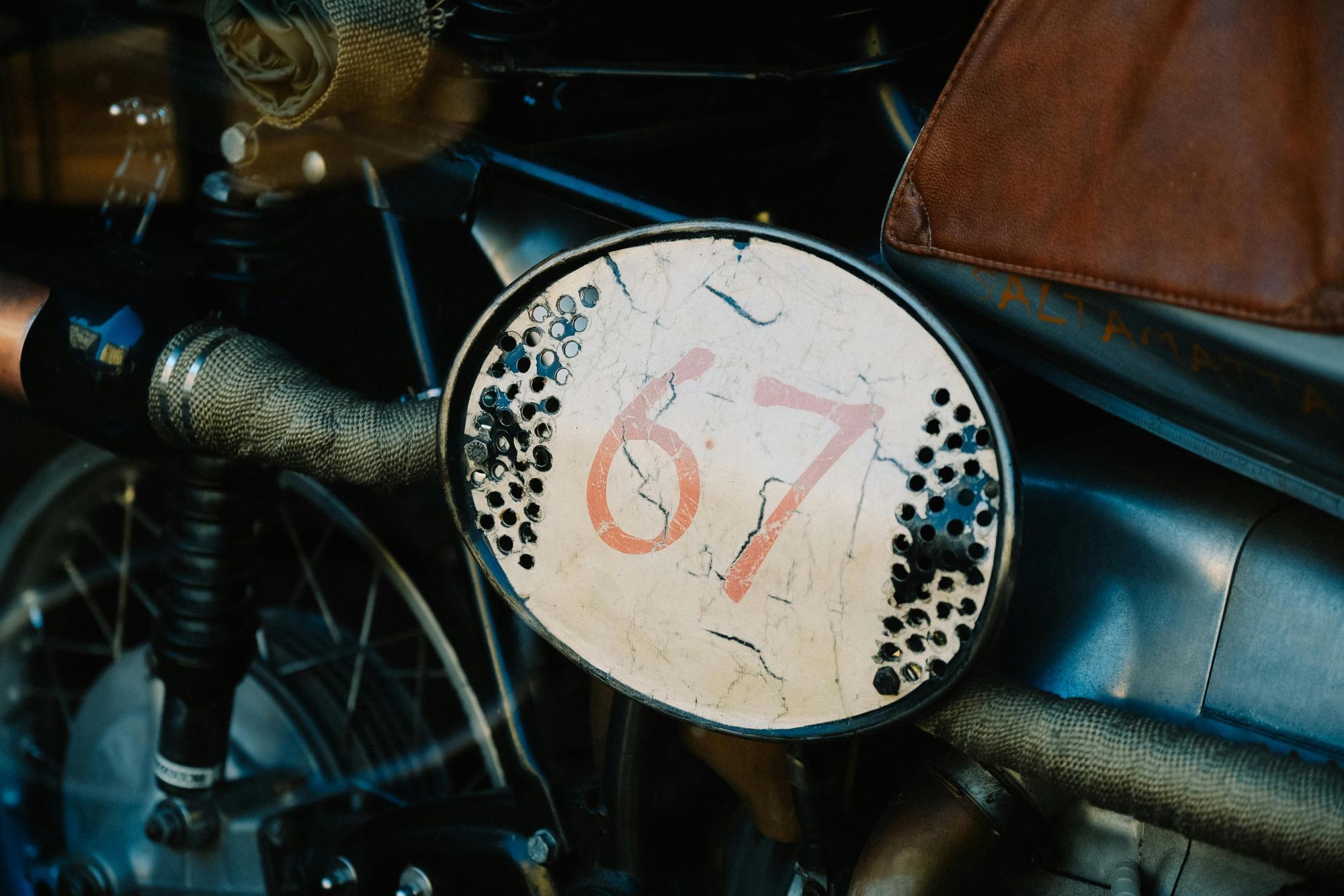Nahaufnahme einer Motorradseite mit der Nummer 67 auf einem ovalen Schild.