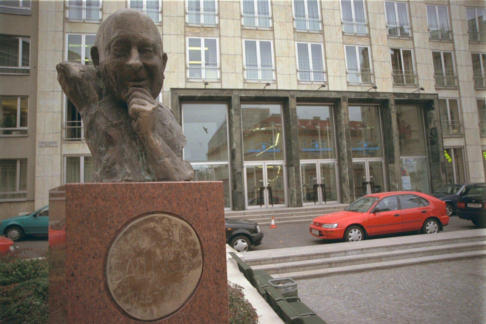 Die Fassade des gewerbehauses von außen, davor steht eine Statue von Rudolf Sallinger. 