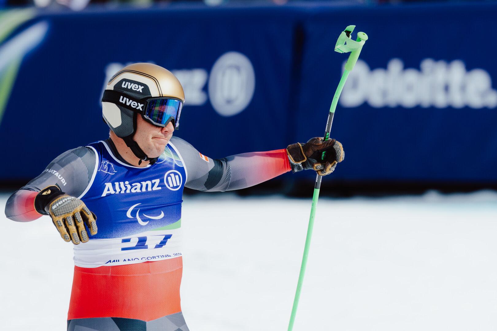Markus Salcher mit Helm und Skibrille hält einen Skistock in der Hand.