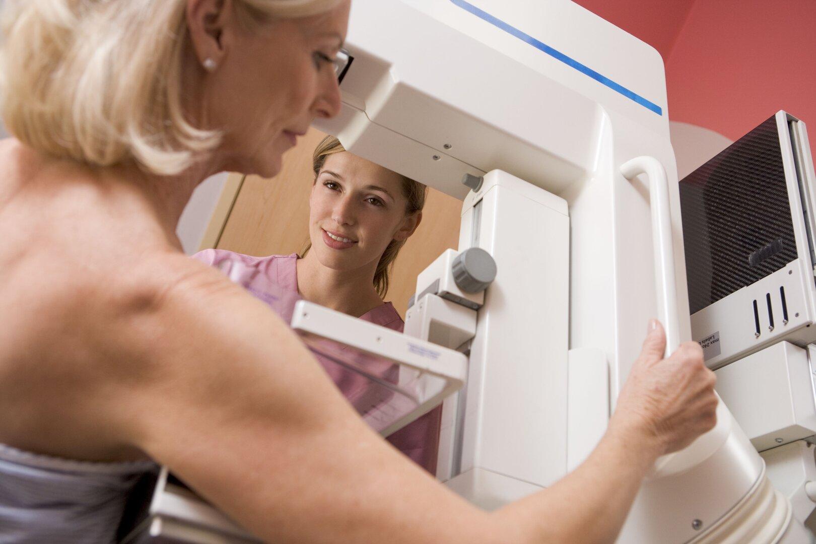 Nurse helping an older patient undergoing a mammogram