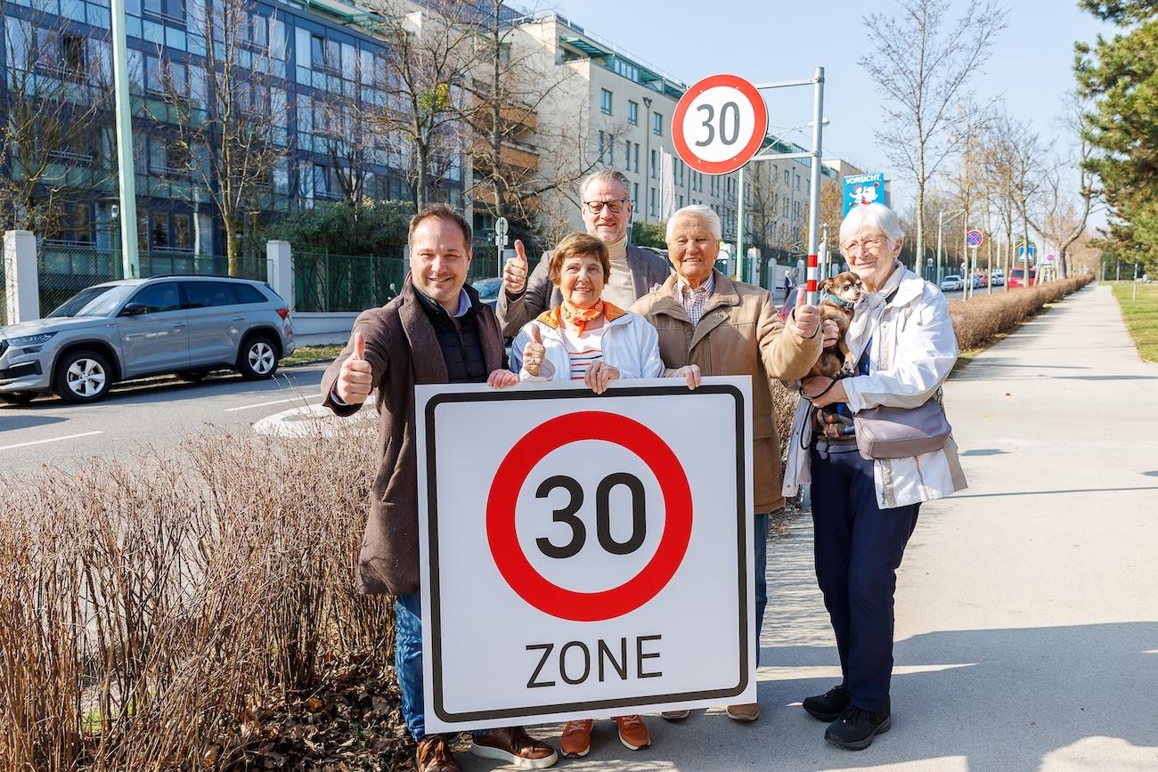 Bezirksvorsteher Daniel Resch und Senioren stehen mit einem Temp-30-Schild und Daumen hoch auf der Straße.