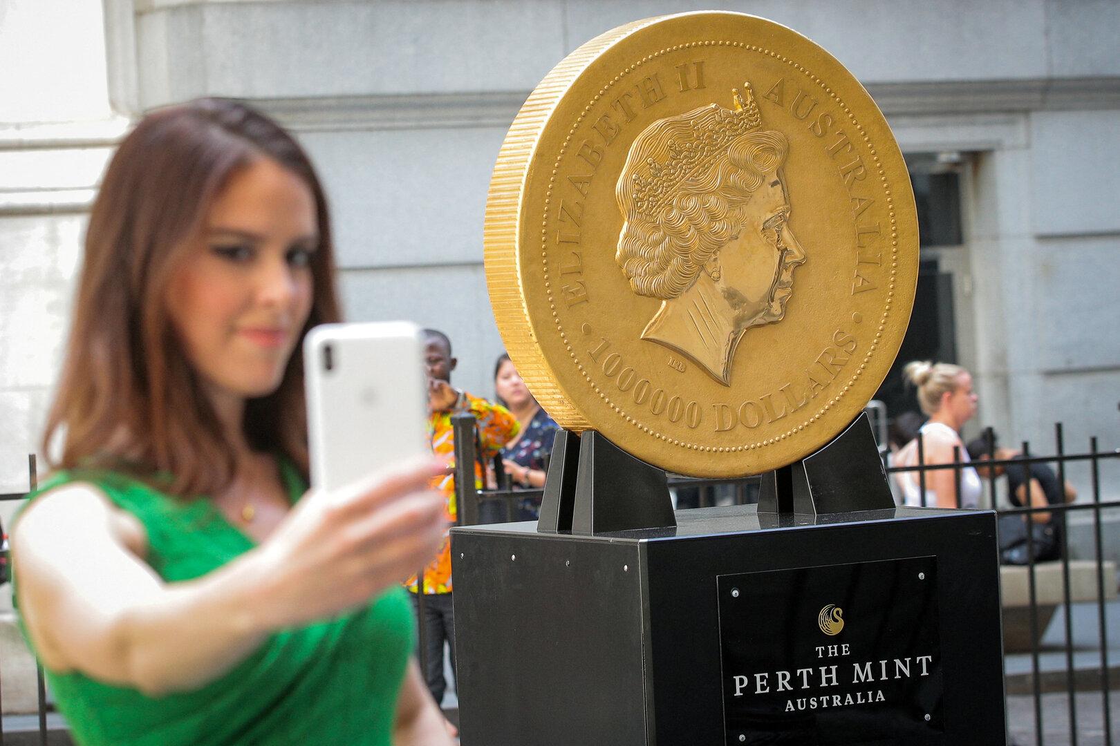 FILE PHOTO: A woman takes a selfie with the world's  largest gold bullion coin, the Australian Kangaroo One Tonne Gold Coin, is displayed outside the NYSE in New York