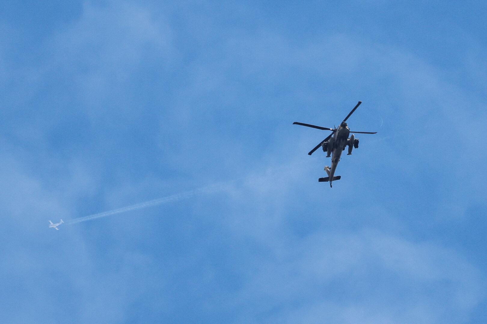 A plane flies overhead an Israeli Apache helicopter near the Israeli  of the border with Lebanon, amid escalation between Iran-backed Hezbollah and Israel and the U.S.-Israeli conflict with Iran