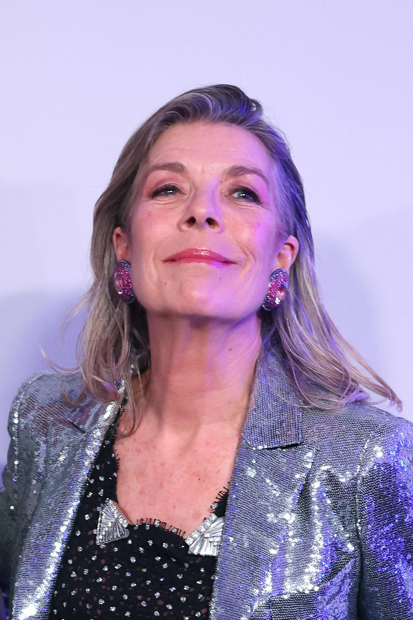 Caroline von Monaco mit blondem Haar trägt einen glitzernden Blazer und auffällige Ohrringe.