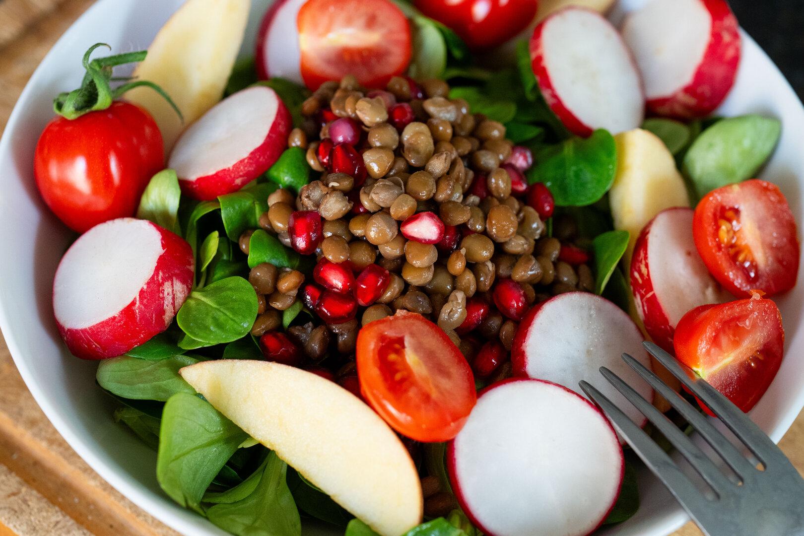 Eine Schüssel mit Salat, Gemüse und Linsen.
