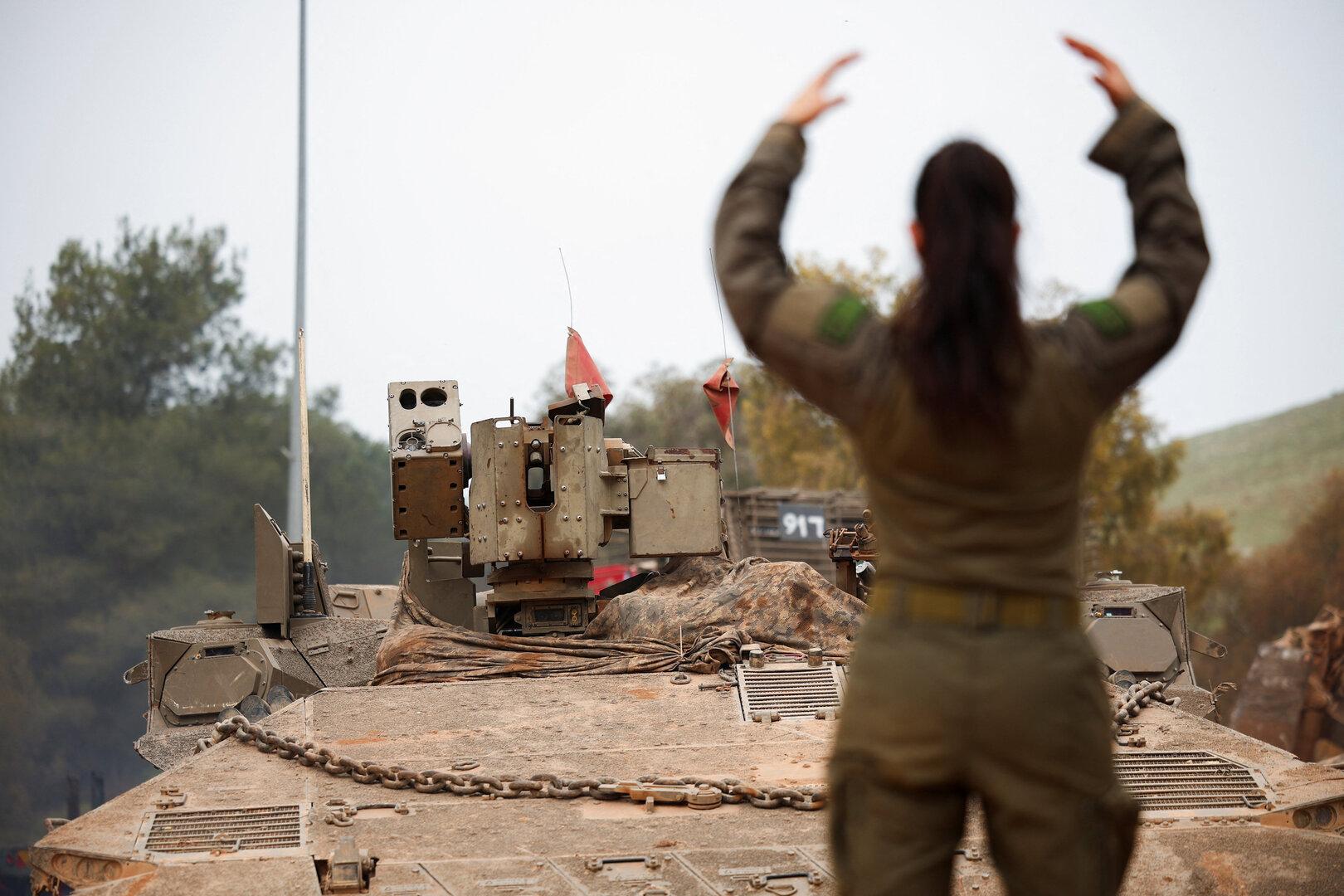 Eine Person in Militäruniform steht mit erhobenen Armen vor einem Panzer, im Hintergrund Bäume und Hügel.