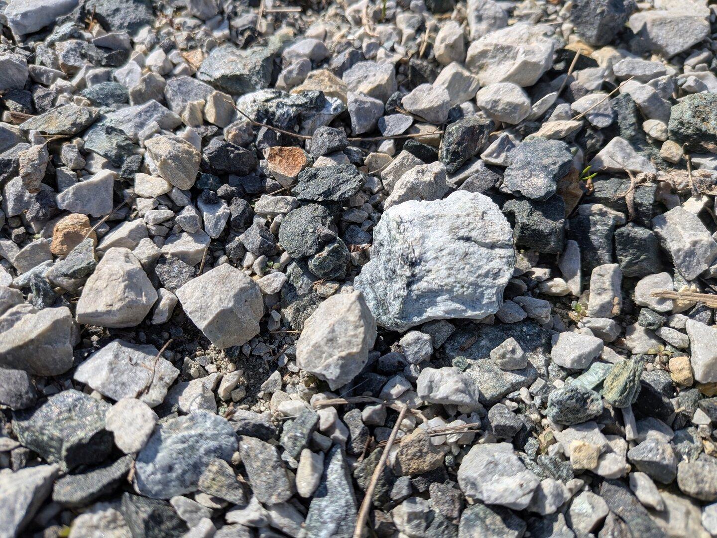 Viele kleine, unterschiedlich geformte Steine in verschiedenen Grautönen liegen dicht nebeneinander auf dem Boden.