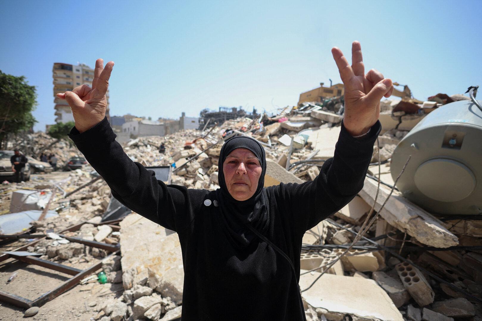 A woman makes a peace sign at the site of an Israeli strike carried out before a 10-day ceasefire between Lebanon and Israel went into effect, in Tyre