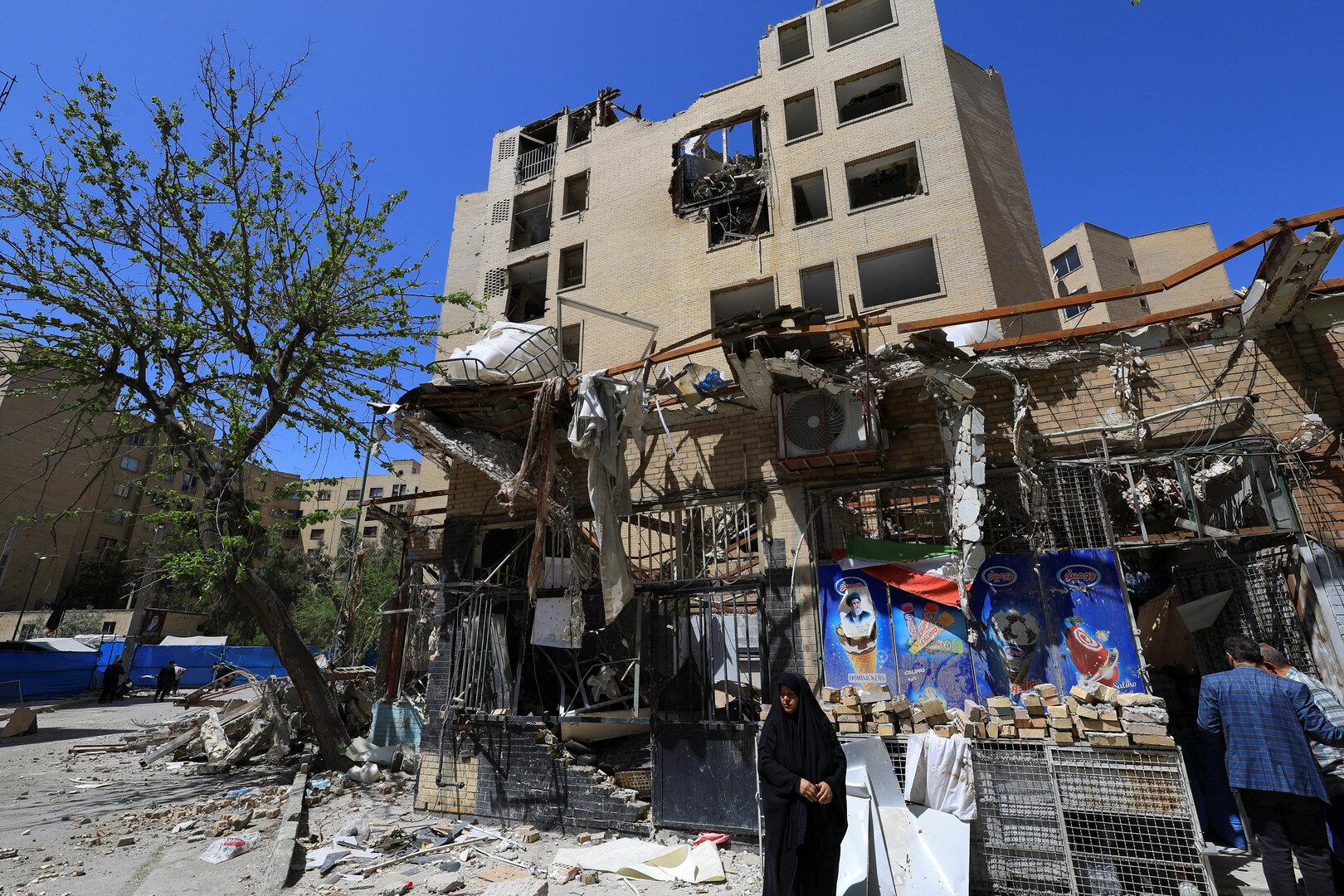 A woman stands next to debris lying in front of a residential building damaged by a strike on March 4, in Tehran