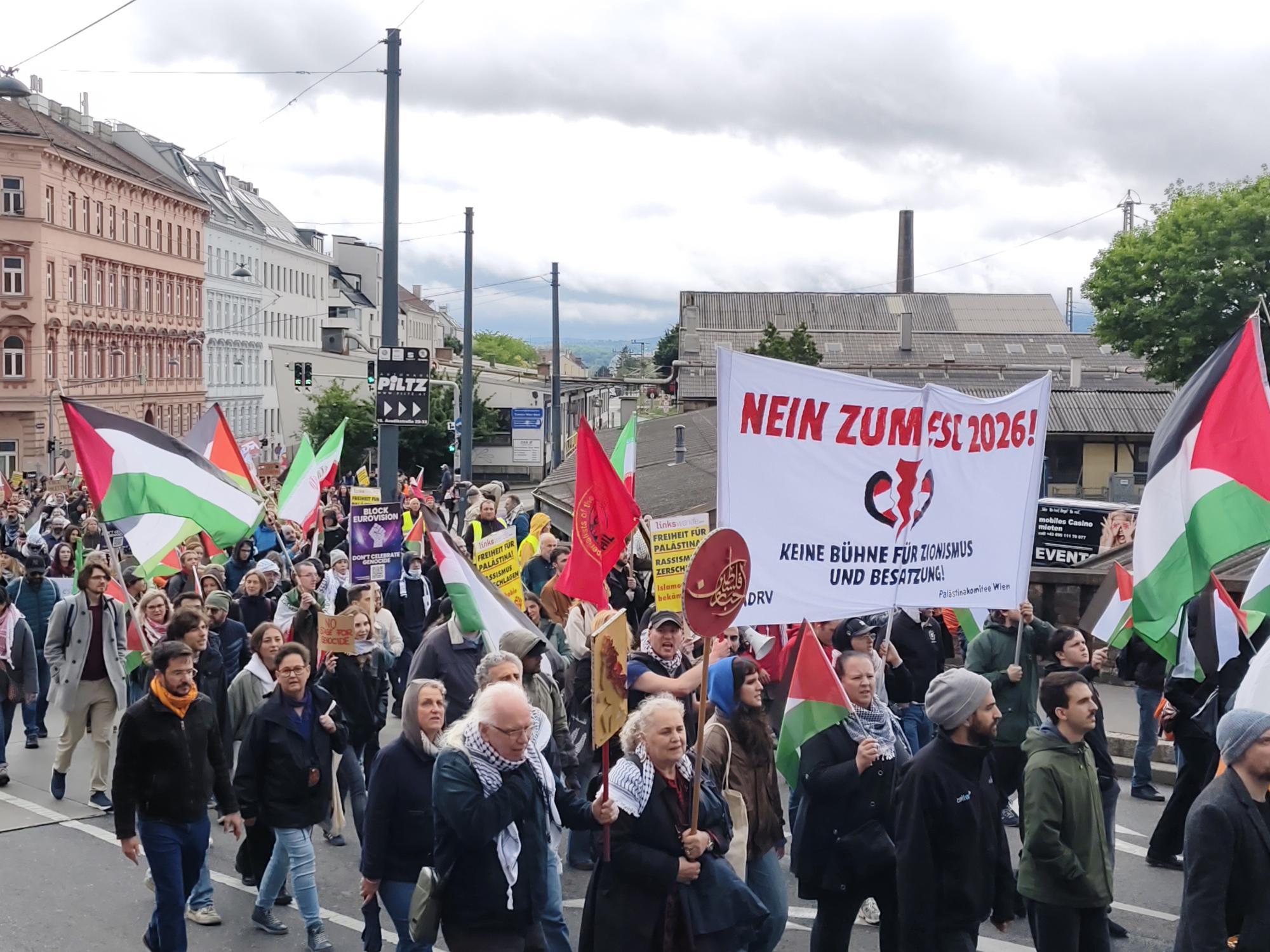 Demonstrierende Menschen mit palästinensischen Fahnen und Transparenten protestieren gemeinsam auf einer Straße.