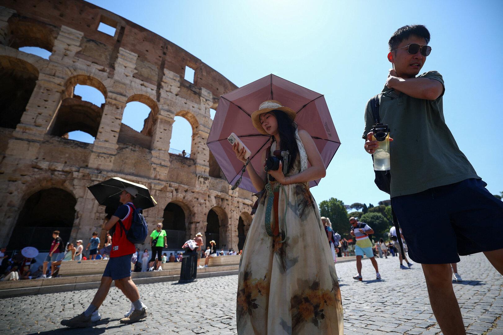 Near the Temple of Claudiuss underground spaces, tourists brave the heat at Romes Colosseum