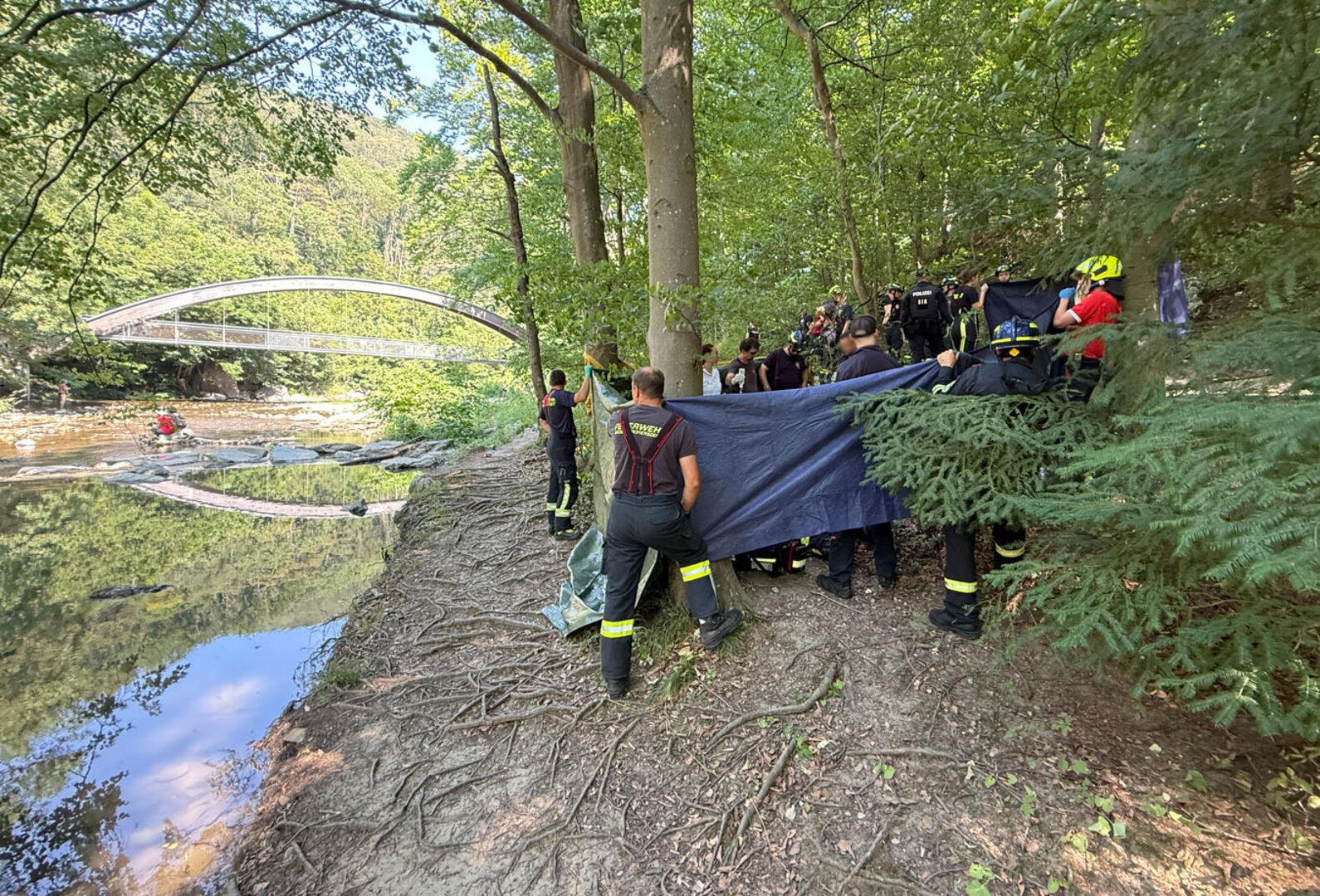 Feuerwehrleute schirmen eine Unfallstelle neben einem Fluß ab