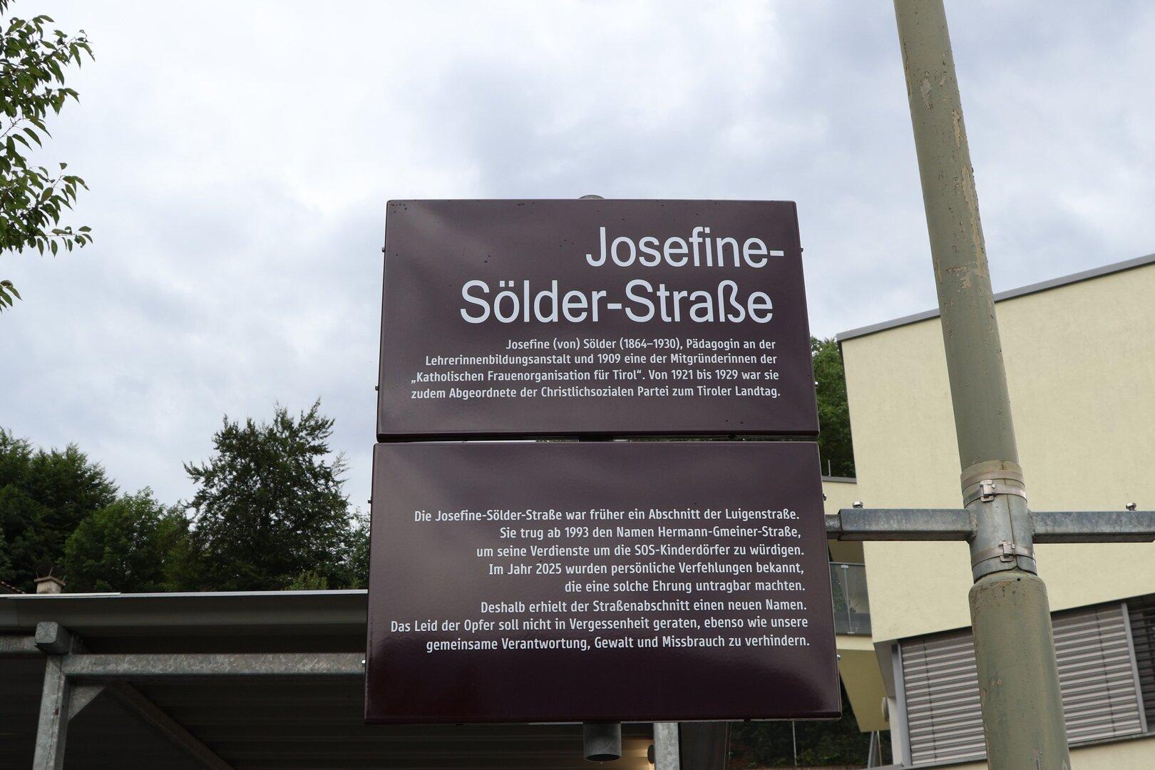 Straßenschild „Josefine-Sölder-Straße“ mit erklärendem Text auf braunem Schild.