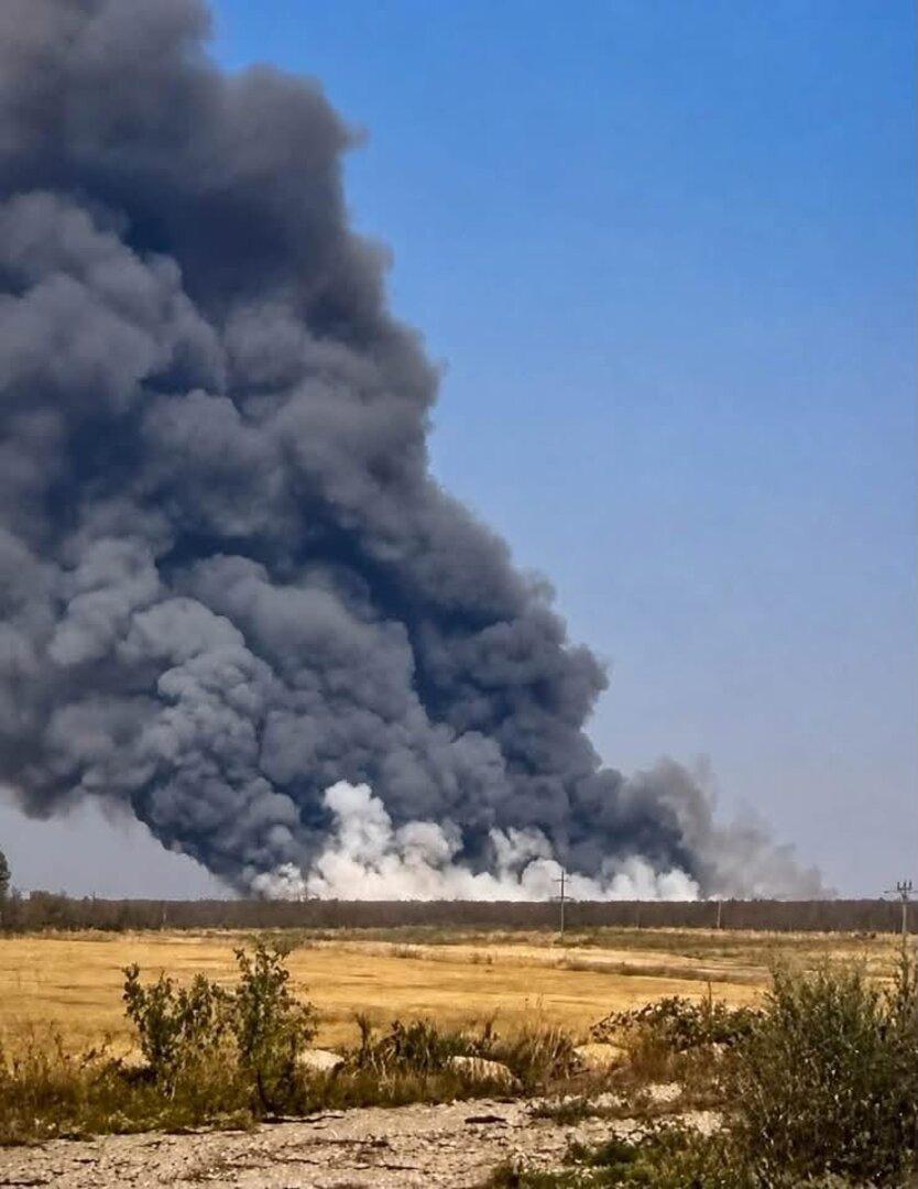 Dicker schwarzer Rauch steigt hinter einer trockenen Landschaft in den Himmel.