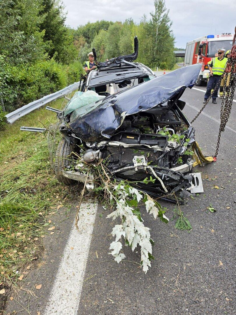 Schwer verunfalltes Auto auf der Straße, Einsatzkräfte sichern die Unfallstelle.
